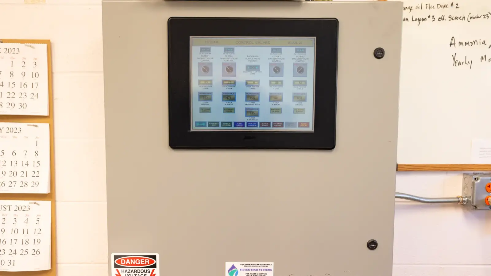 A touchscreen displaying valve and process controls on a real wastewater SCADA cabinet